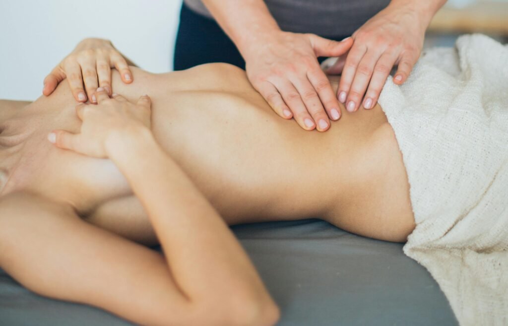 gros plan de mains en train de faire un drainage lymphatique brésilien sur le ventre d'une cliente